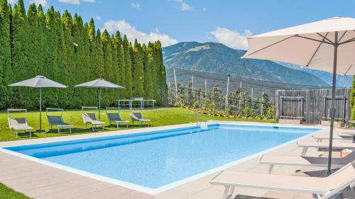 - une piscine avec des chaises et un parasol dans l'établissement Residence Ferienwohnungen Sonnegg, à Vollan