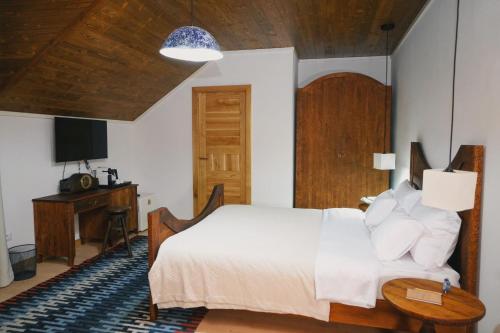 a bedroom with a white bed and a desk at Conacul Sanct Gurgh in Cormaia