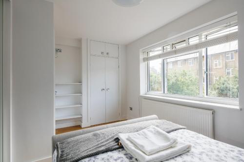 um quarto branco com uma cama e uma janela em Bright & welcoming garden flat sleeps 6 in style em Londres