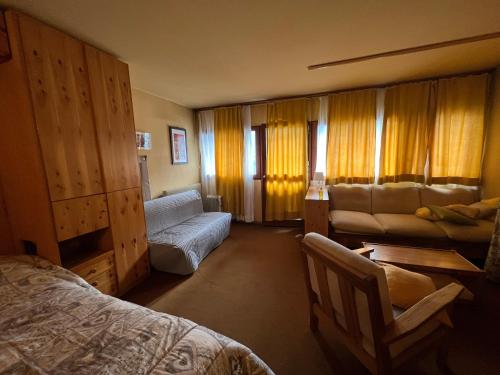 a bedroom with a bed and a couch and a chair at Appartamento I Dadi Cervinia in Breuil-Cervinia
