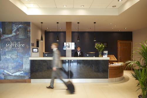 a man walking past a counter in a lobby at Mercure Sheffield Parkway in Sheffield