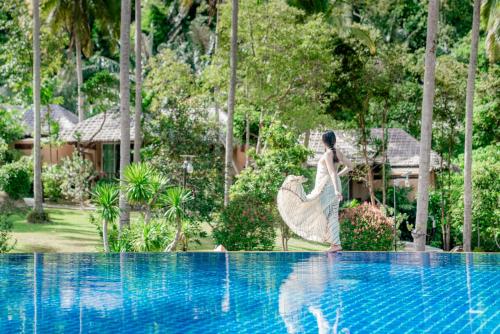 uma mulher de vestido ao lado de uma piscina em Ban Sainai Resort- SHA Extra Plus Aonang's Green Resort em Praia de Aonang