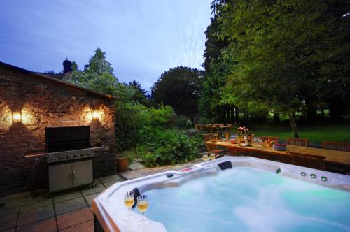 uma banheira de hidromassagem num quintal com uma mesa e comodidades para churrascos em Upside house Beautiful 5 bedroom house sleeps 13 with hottub, games room and garden near Bath em Shepton Mallet