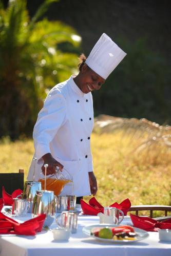 a chef standing next to a table with food at Elewana Lewa Safari Camp in Meru