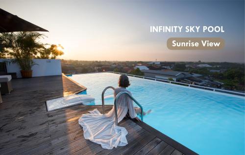 a woman in a dress is standing next to a swimming pool at Infinity8 Bali in Jimbaran