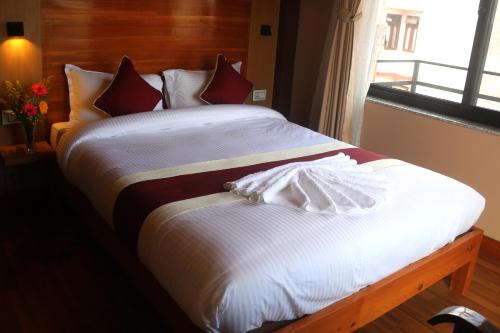 a bed with white sheets and red pillows next to a window at Hotel Family Ties Pvt. Ltd. in Kathmandu