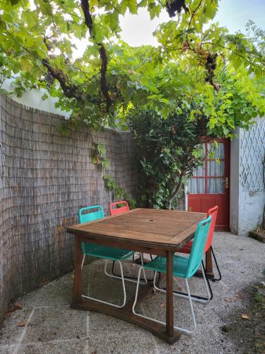 ein Holztisch mit vier Stühlen um ihn herum in der Unterkunft La maison rouge paisible maison de pays in Saujon