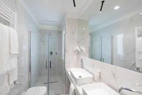 baño blanco con ducha y lavamanos en Hotel Fiorentina, en Nápoles