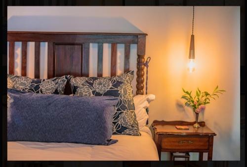 a bedroom with a bed with pillows and a night stand at Die Hof Gastehuis in Kroonstad