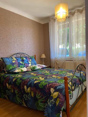 une chambre avec un lit avec une couette colorée et une fenêtre dans l'établissement Claire fontaine, à Beaumont-du-Périgord