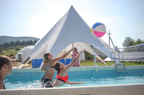 een groep mensen die volleyballen in een zwembad bij Глемпінг Едельвейс in Oryavchyk