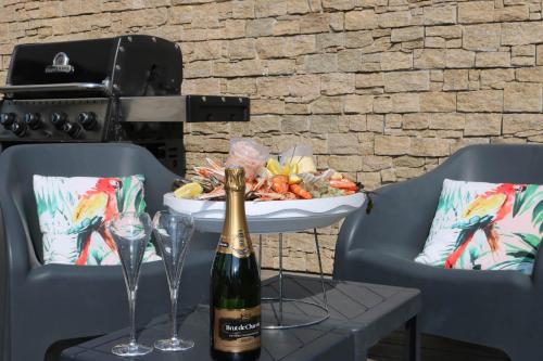 a bottle of champagne sitting on a table with two glasses at La Villa Thelma 5 étoiles, piscine, sauna et jacuzzi in Granville