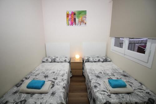 2 Einzelbetten in einem kleinen Zimmer mit Fenster in der Unterkunft Urgel habitaciones in Barcelona