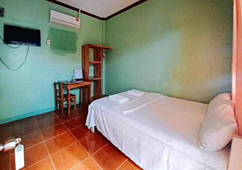 een slaapkamer met een wit bed en een tafel bij RedDoorz at July's Haven Seaside Pension Camiguin in Mambajao