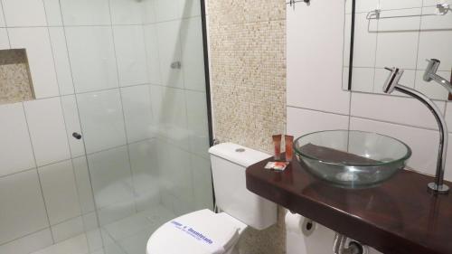 a bathroom with a toilet and a glass bowl on a counter at Costa Dourada Pousada in Arraial do Cabo