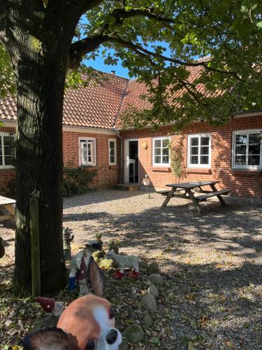a cow standing under a tree in front of a house at Familiehuis Boysen Bed&Breakfast in Ribe
