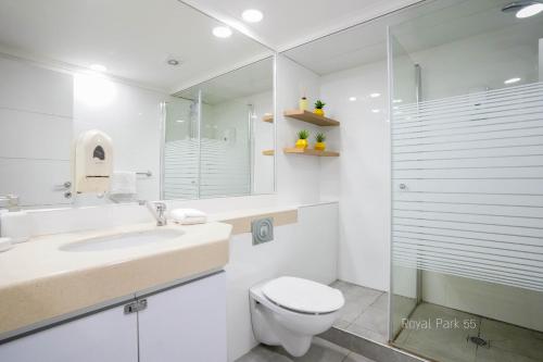 a white bathroom with a toilet and a sink at YalaRent Royal Park Resort Complex Apartments in Eilat