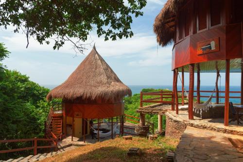 a small hut with a thatched roof next to a building at Ecohabs Tequendama - Parque Tayrona in El Zaino