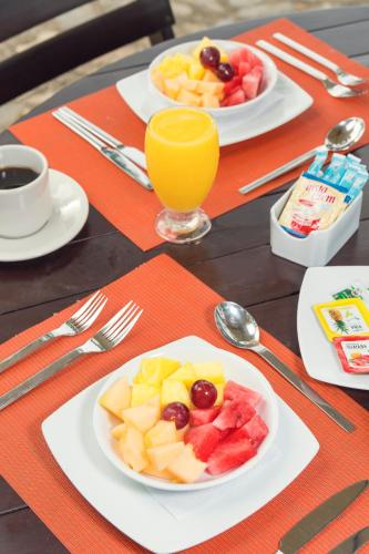 a table with plates of fruit and a glass of orange juice at Ecohabs Tequendama - Parque Tayrona in El Zaino