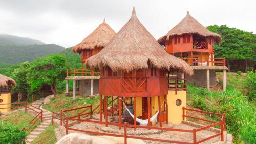 a group of huts with straw roofs on a hill at Ecohabs Tequendama - Parque Tayrona in El Zaino