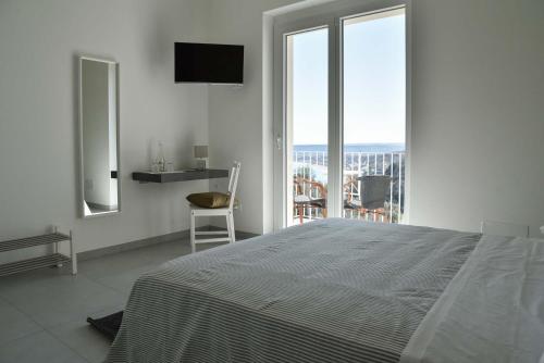 a white bedroom with a large bed and a balcony at Villa Caravaggio Comfort e Relax in Rocca San Giovanni