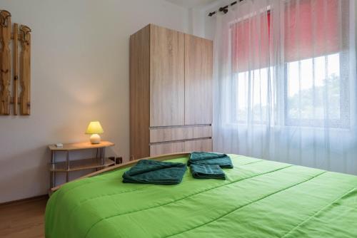 Un dormitorio con una cama verde y una ventana. en Villa ADORA, en Balchik