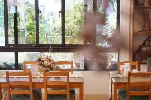 uma sala de jantar com mesa, cadeiras e janelas em Pottery Flower B&B em Jiji