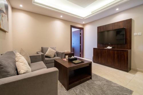 a living room with a couch and a flat screen tv at Luxury Hospitality Serviced Apartments in Al Khobar