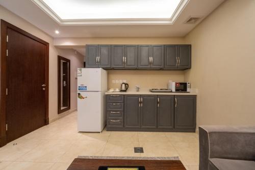 a kitchen with black cabinets and a white refrigerator at Luxury Hospitality Serviced Apartments in Al Khobar
