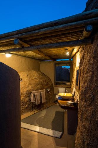 a bathroom with a stone wall and a sink at Mowani Mountain Camp in Khorixas