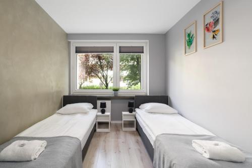 2 camas en una habitación con ventana en Family Apartment Poznań Rataje by Renters en Poznan