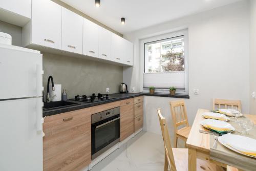 a kitchen with white cabinets and a wooden table with a dining room at Family Apartment Poznań Rataje by Renters in Poznań