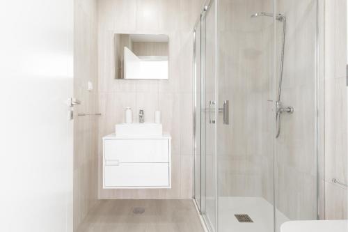 a white bathroom with a shower and a sink at Dino Villa in Casal do Cigano