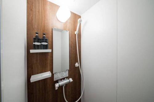 uma casa de banho com um chuveiro e um espelho. em The PLAZA HOTEL S4W12 em Sapporo
