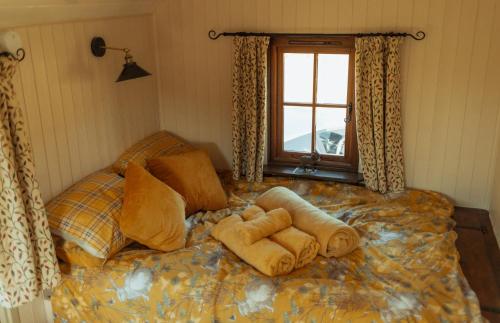 a bed with towels on it with a window at Glamping in Wiltshire in our luxury Shepherds Hut in Chippenham
