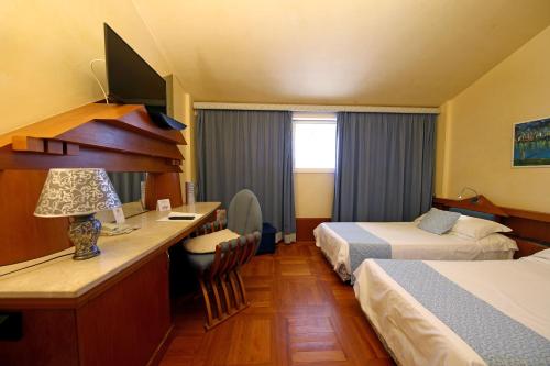 a hotel room with two beds and a desk at HR Hotel in Monfalcone