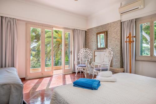 a bedroom with a bed and chairs and windows at Villa Claramunda in Cala D'or