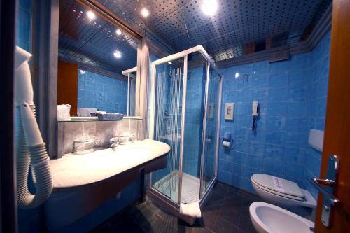 a blue bathroom with a sink and a shower at HR Hotel in Monfalcone