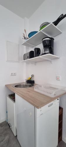 eine Küche mit einer Theke mit einer Spüle und Regalen in der Unterkunft Appartement Hertha in Celle
