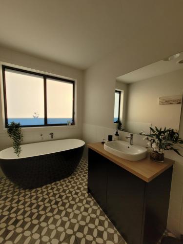 La salle de bains est pourvue d'une baignoire, d'un lavabo et d'une grande fenêtre. dans l'établissement New apartment 3 min to Sovereign Hill & Wildlife Park, à Ballarat