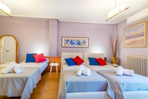 Cette chambre comprend 4 lits avec des oreillers bleus et rouges. dans l'établissement Apartamento VIRGEN DEL VALLE, à Cenicero