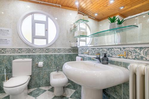 uma casa de banho com um lavatório, um WC e uma janela. em Apartamento VIRGEN DEL VALLE em Cenicero