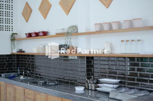 a kitchen with black tiled walls and a counter at Pringgading Surf Camp Mitra RedDoorz in Bengkulu