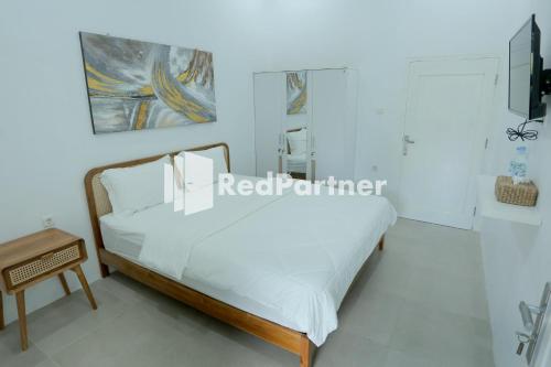 a white bedroom with a bed and a table at Pringgading Surf Camp Bengkulu Mitra RedDoorz in Bengkulu