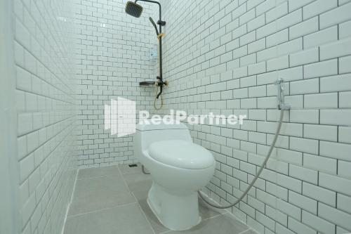 a bathroom with a toilet with a hose at Pringgading Surf Camp Bengkulu Mitra RedDoorz in Bengkulu