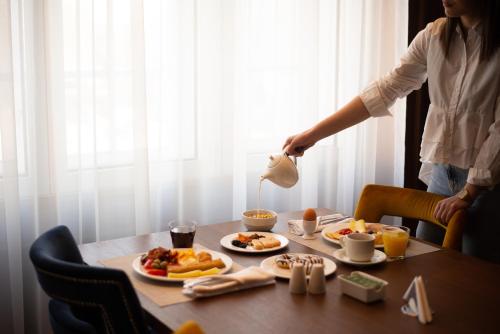 a woman is pouring milk into a table of food at Hotel Centar No.1 in Belgrade