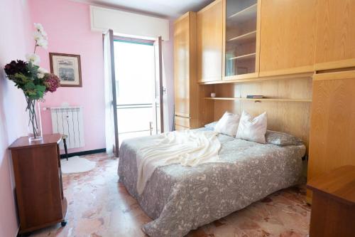 um quarto com uma cama e um vaso de flores em [VIA CRISPI] Grande e comodo in zona tranquilla. em Pietra Ligure