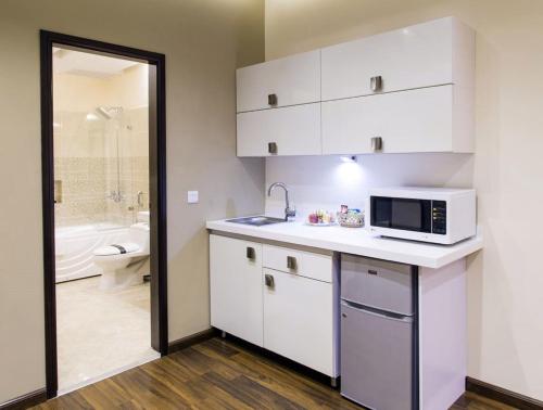 a kitchen with a microwave on a counter with a bathroom at Royaute Luxury Suites and Hotel Gulberg Lahore in Lahore