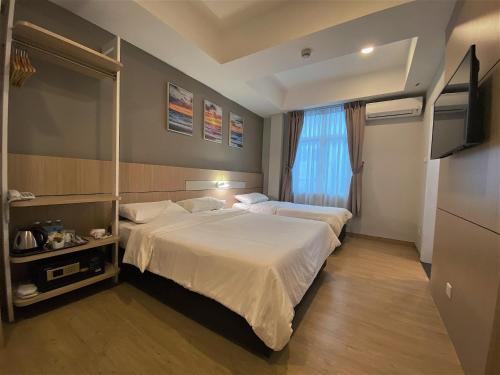 a hotel room with two beds and a television at Walk In Hotel in Kota Kinabalu