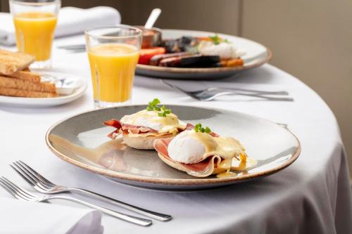 a table with two plates of breakfast foods and orange juice at Honest Lawyer Hotel in Durham